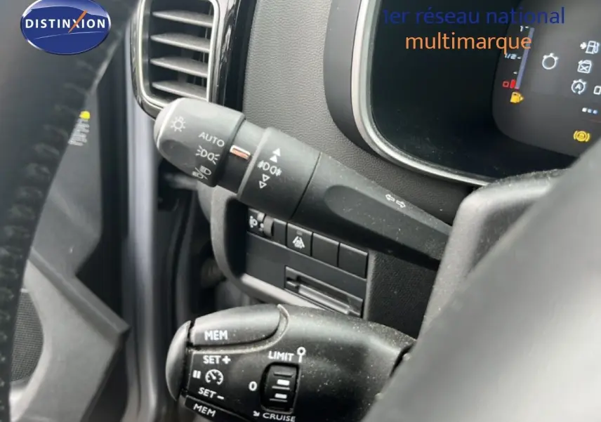 Gros plan sur les commandes au volant du Citroën C5 Aircross gris clair, mettant en valeur les fonctions de régulateur et éclairage.