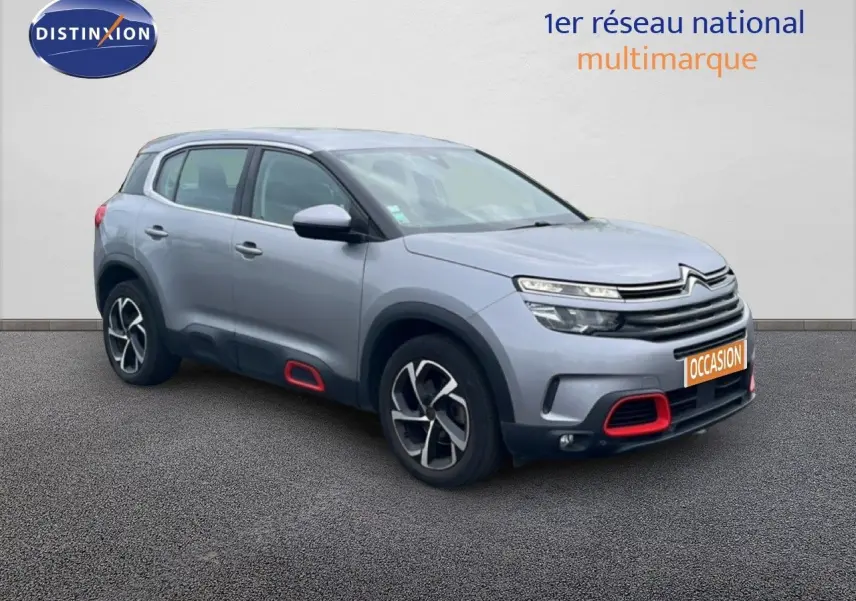 Vue 3/4 avant d’un Citroën C5 Aircross gris clair métal avec détails rouges sur pare-chocs et bas de porte.