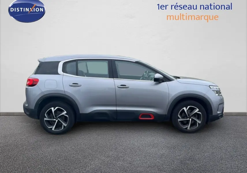 Vue de profil côté gauche d'un Citroën C5 Aircross gris clair métal avec détails noirs et rouge sous les portes.