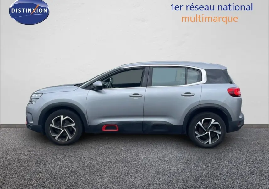 Profil droit d'un Citroën C5 Aircross gris clair métal avec détails rouges sur les bas de caisse et jantes stylisées.