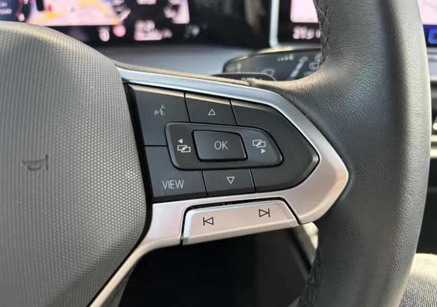 Gros plan sur les commandes à droite du volant noir de la Volkswagen Golf 1.5 eTSI 2024 avec écran digital en arrière-plan.