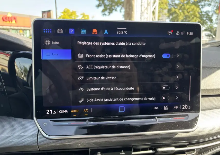 Écran tactile central affichant les réglages d’aide à la conduite dans une Volkswagen Golf blanche, vue intérieure.