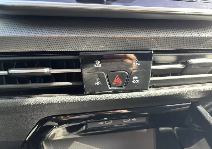 Détail du tableau de bord noir de la Volkswagen Golf 2024 montrant les commandes d'assistance et climatisation.