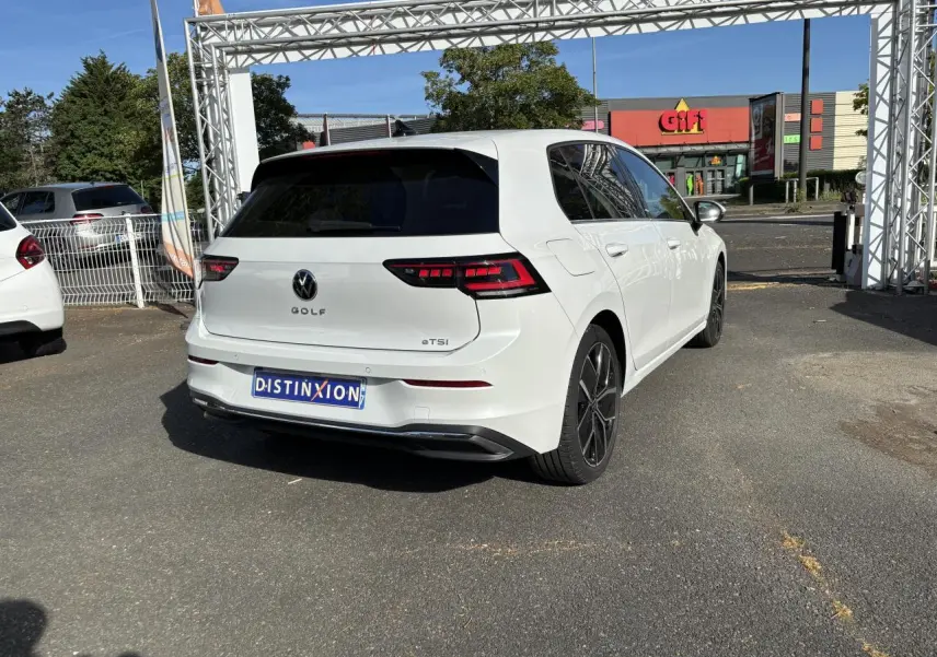 Vue 3/4 arrière droite d'une Volkswagen Golf blanche avec feux arrière LED et jantes alliage 18 pouces.