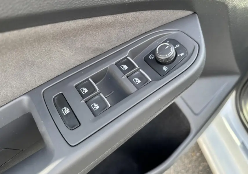 Vue rapprochée des commandes des vitres et des rétroviseurs sur la porte avant gauche d’une Volkswagen Golf blanche 2024.