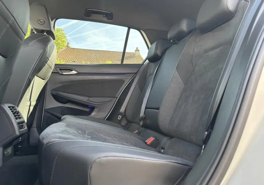 Vue latérale intérieure côté droit des sièges arrière en cuir noir de la Volkswagen Golf 2024 blanche.