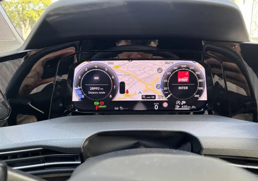 Vue rapprochée du combiné d'instruments digital couleur de la Volkswagen Golf 1.5 eTSI 2024 affichant la navigation et les compteurs.