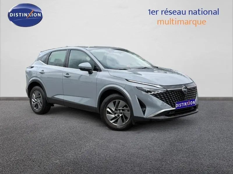 Nissan Qashqai 1.3 Mild Hybrid gris Argile en 3/4 avant droit, avec calandre noire et jantes alu.