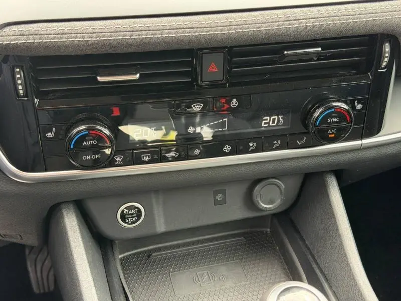 Vue rapprochée de la console centrale du Nissan Qashqai gris Argile, montrant la climatisation automatique bi-zone et le bouton start/stop.