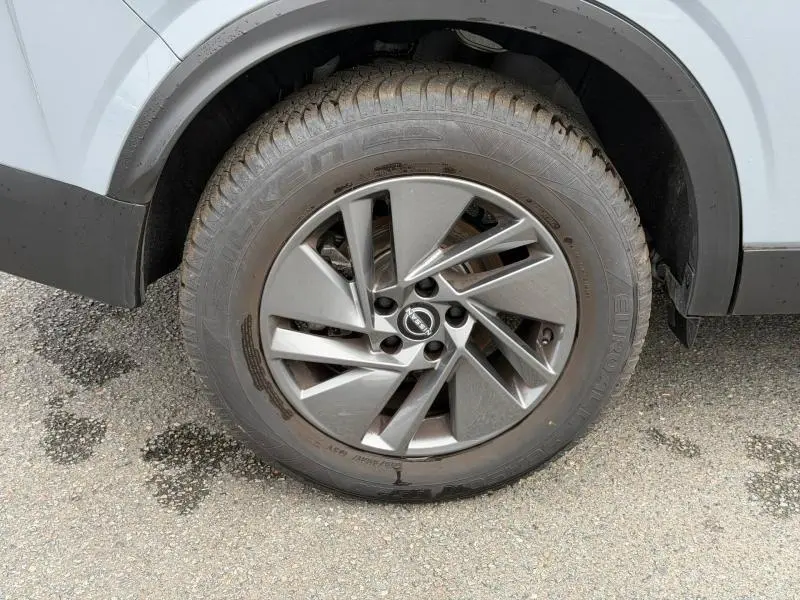 Gros plan sur la roue avant droite du Nissan Qashqai 2025 gris Argile avec jante alu au design moderne.