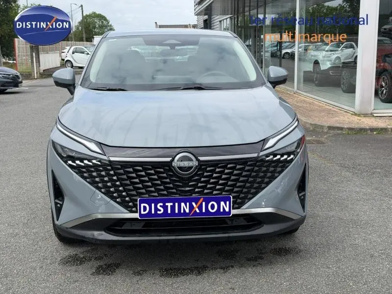 Vue avant d'un Nissan Qashqai 1.3 Mild Hybrid gris Argile avec calandre noire et phares LED fins.