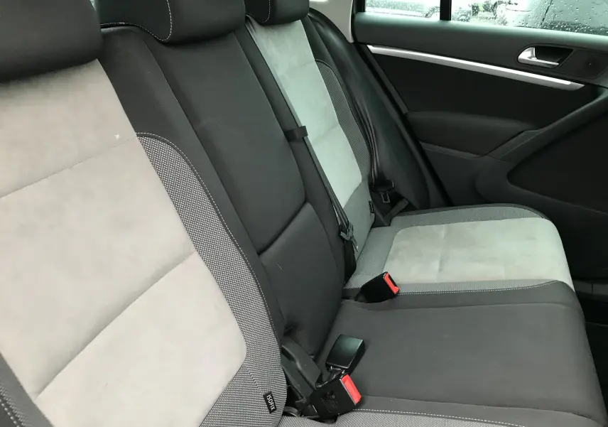 Vue intérieure des sièges arrière en tissu gris clair et noir du Volkswagen Tiguan Sportline 2012, avec ceintures et appuie-têtes visibles.