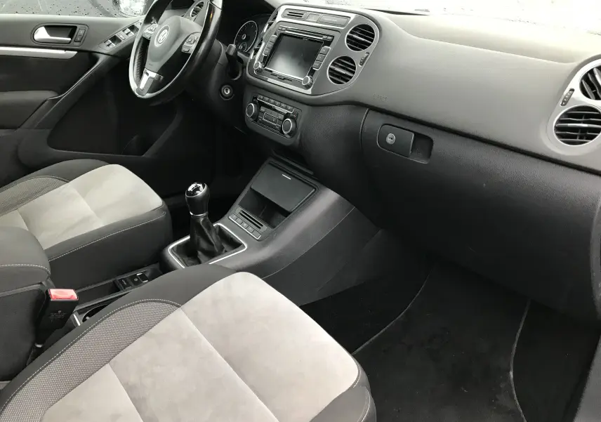 Intérieur avant du Volkswagen Tiguan Sportline 2012, vue côté passager avec sièges tissu gris clair et volant multifonctions noir.
