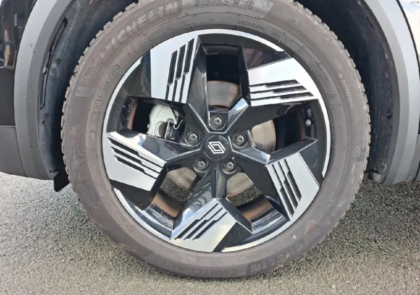 Gros plan sur la roue avant gauche de la Renault SYMBIOZ noire, jante alliage noire et argentée au design géométrique.