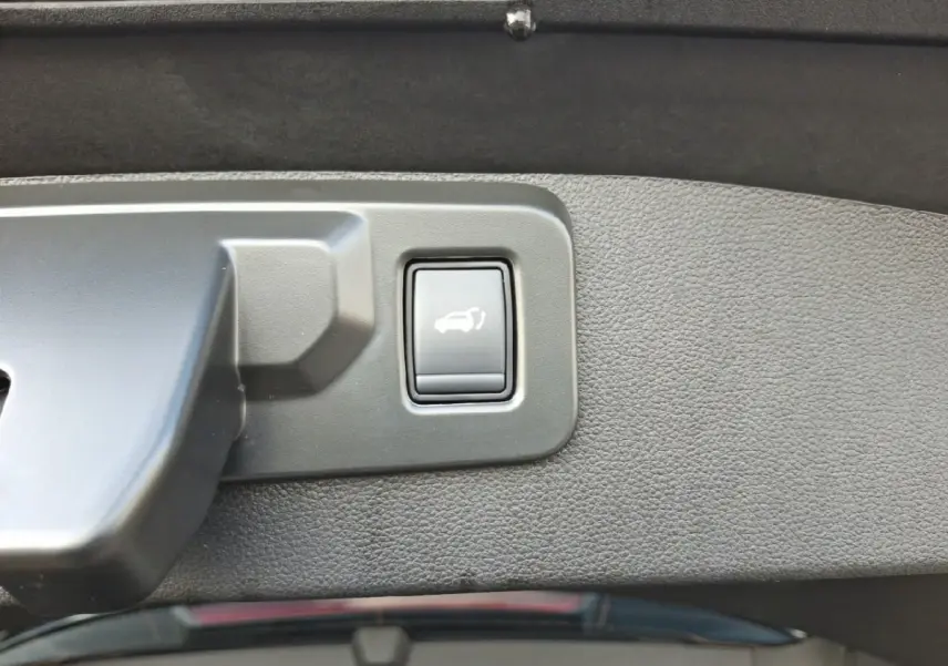 Gros plan sur le bouton d'ouverture électrique du coffre dans l'intérieur noir du Renault Symbioz Iconic E-Tech 2025.