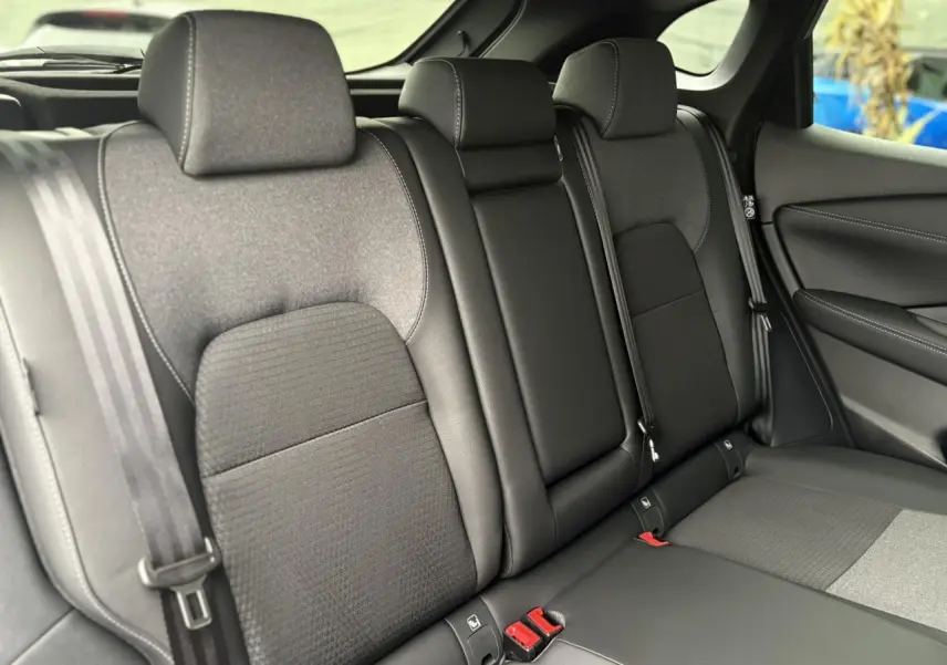 Vue latérale intérieure des sièges arrière gris et noirs du Nissan Qashqai 2024 avec ceintures de sécurité visibles.