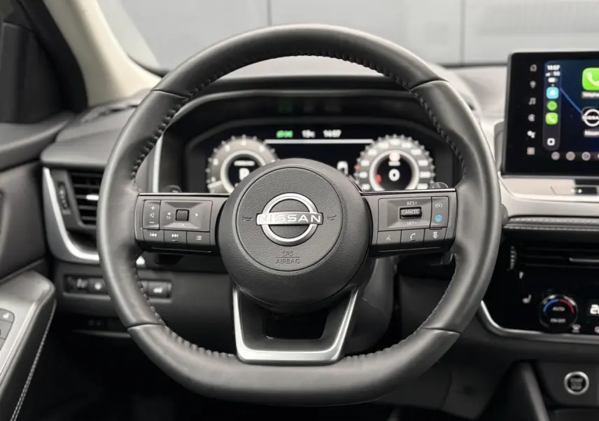 Vue frontale du volant cuir noir Nissan Qashqai 2024 avec commandes intégrées et tableau de bord numérique.