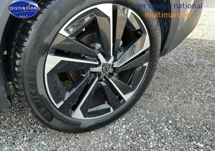 Gros plan sur la jante alu noire et argentée d'une Peugeot 408 Hybrid 145 allure gris sélénite, roue avant droite.