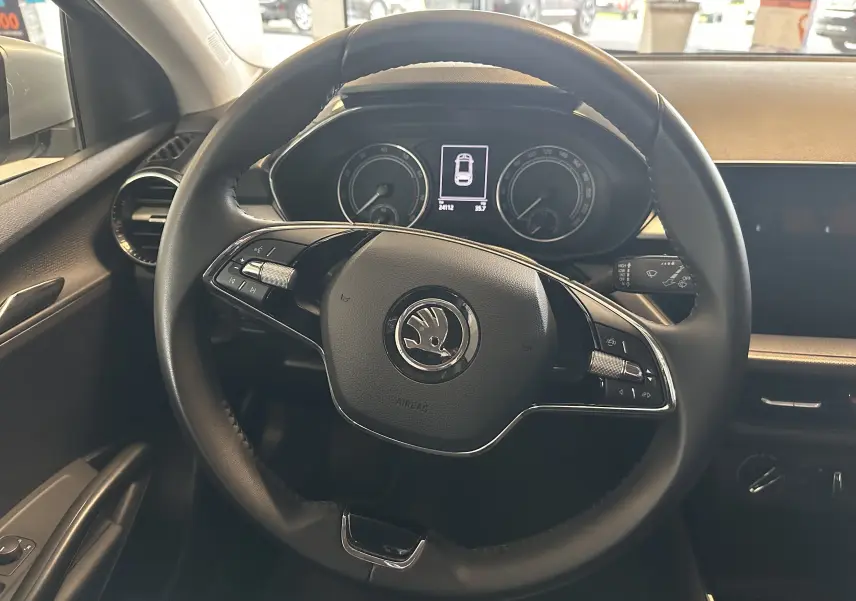 Vue intérieure centrée sur le volant noir d'une Skoda Fabia Ambition 2023 avec tableau de bord numérique et commandes intégrées.