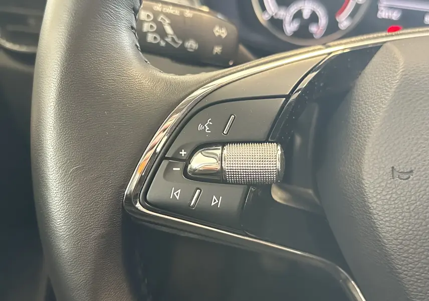Gros plan sur la commande de volume argentée et boutons multifonctions du volant noir de la Skoda Fabia gris 2023.