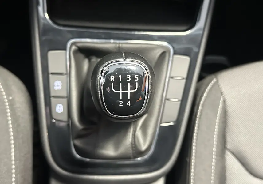 Gros plan sur le levier de vitesse manuel noir de la Skoda Fabia Ambition 2023, entouré de sièges gris clair.