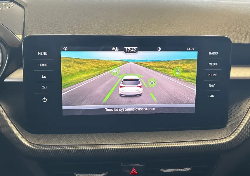 Écran central de la Skoda Fabia Ambition 2023 affichant l'assistance à la conduite avec vue arrière virtuelle du véhicule gris.