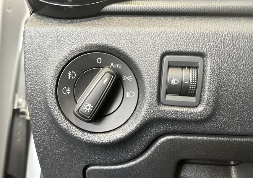 Gros plan sur le bouton de commande des phares et le réglage de l'intensité lumineuse dans une Skoda Fabia Ambition gris 2023.