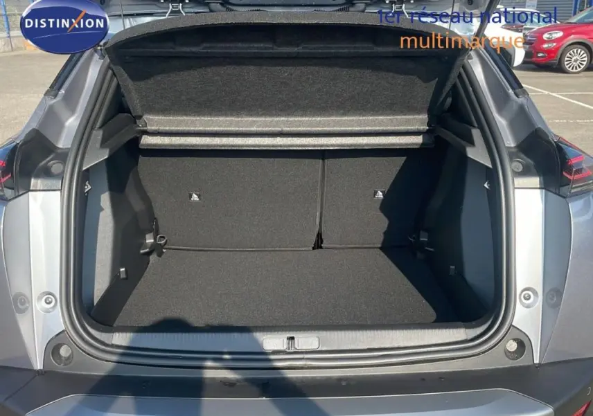 Coffre ouvert vu de l'arrière d'un Peugeot 2008 gris 2025, montrant l'espace de chargement et la tablette cache-bagages.