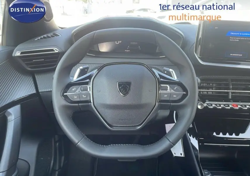 Vue intérieure centrée sur le volant cuir du Peugeot 2008 gris avec commandes au volant et écran tactile visible.