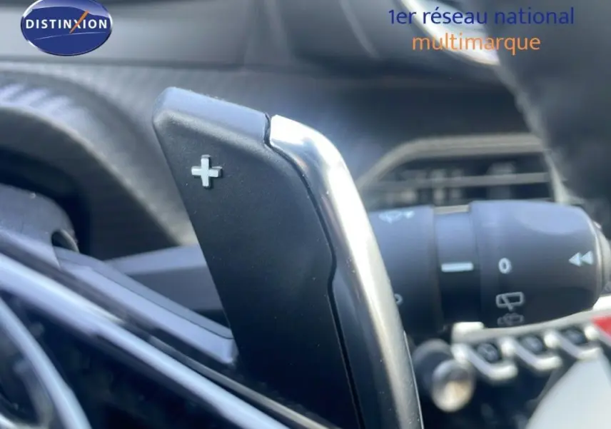 Gros plan sur la palette de changement de vitesse + au volant cuir du Peugeot 2008 gris hybride 2025.