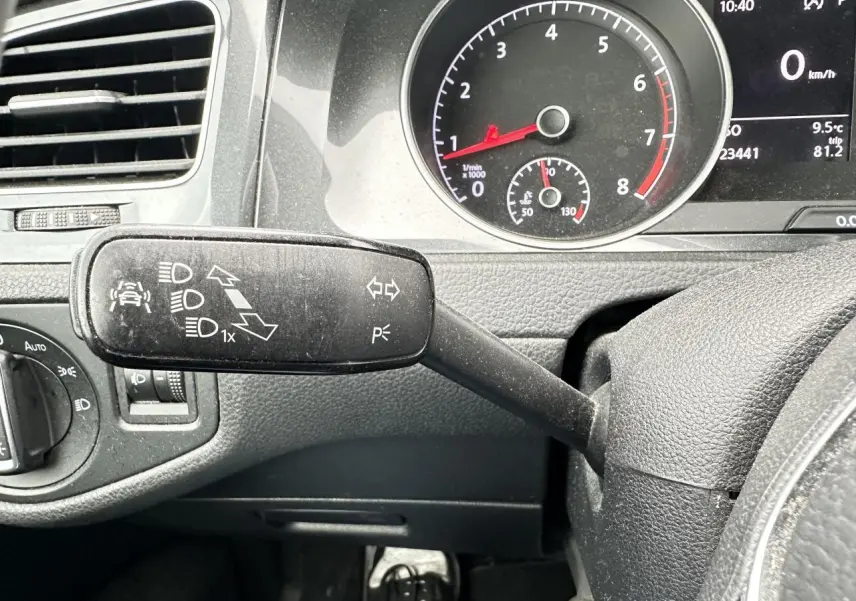 Gros plan sur la manette de clignotant à gauche du volant dans l’habitacle gris foncé d’une Volkswagen Golf VII 2018.