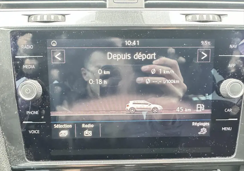 Écran tactile central de la Volkswagen Golf VII gris foncé affichant les données de conduite et la consommation.