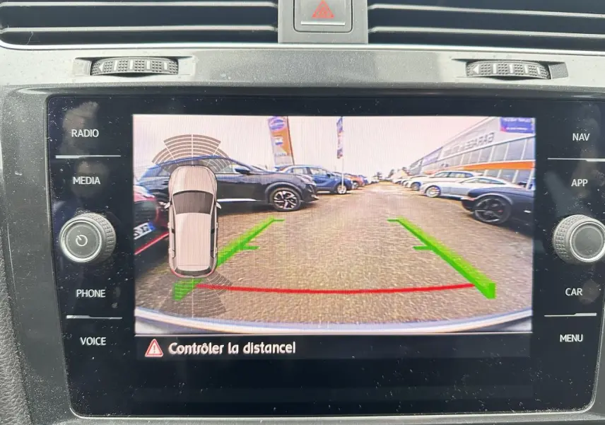 Écran de la radio affichant la caméra de recul d'une Volkswagen Golf gris foncé avec lignes de guidage vertes et rouges.