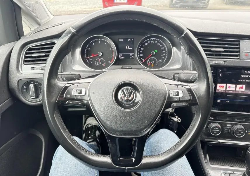 Vue intérieure centrée sur le volant en cuir noir d'une Volkswagen Golf VII avec tableau de bord et écran tactile visibles.