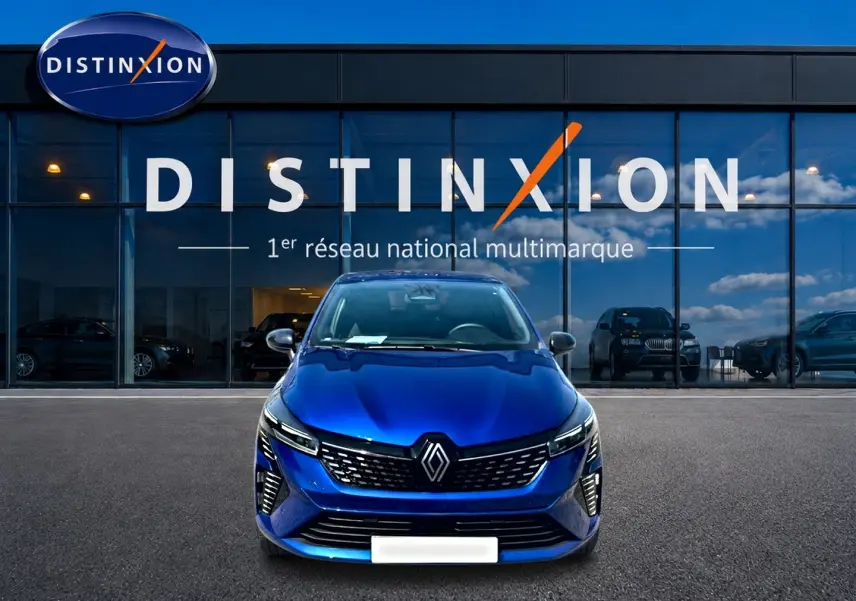 Vue frontale d'une Renault Clio V bleu iron garée devant une vitrine avec logo Distinxion.