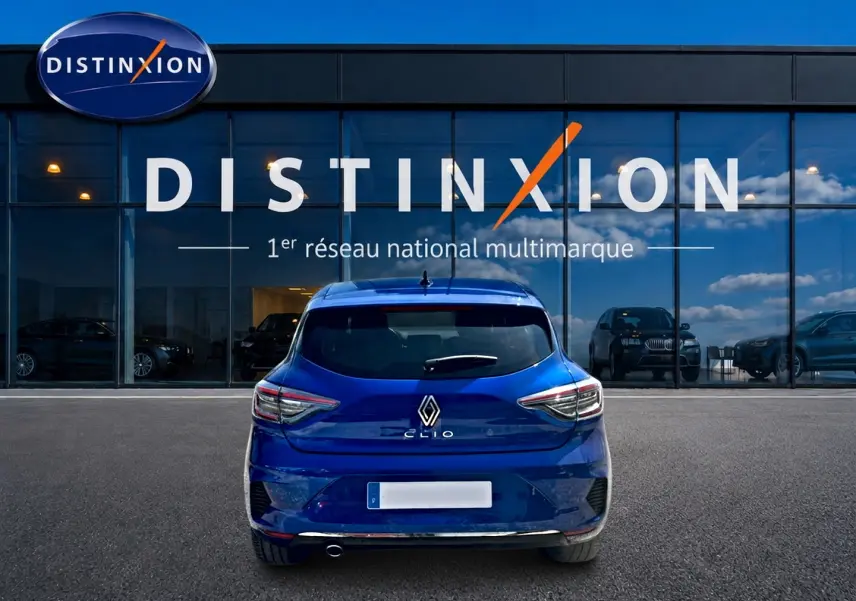 Vue arrière d'une Renault Clio V bleu iron garée devant une vitrine avec logo Distinxion.