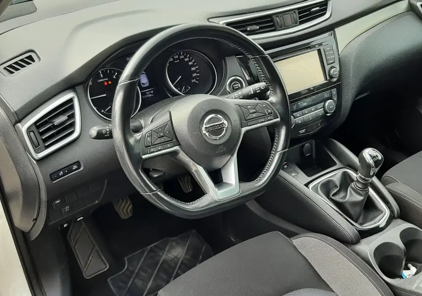 Vue intérieure côté conducteur du Nissan Qashqai 1.5 DCI 115ch N-Connecta 2018, volant cuir, boîte manuelle et tableau de bord noir.