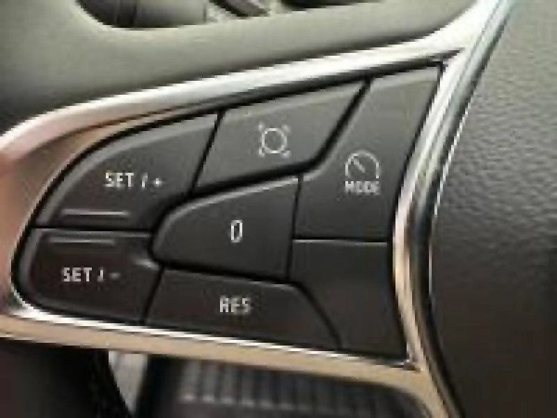 Gros plan sur les commandes noires du volant multifonction du Renault Captur rouge, avec finitions chromées.