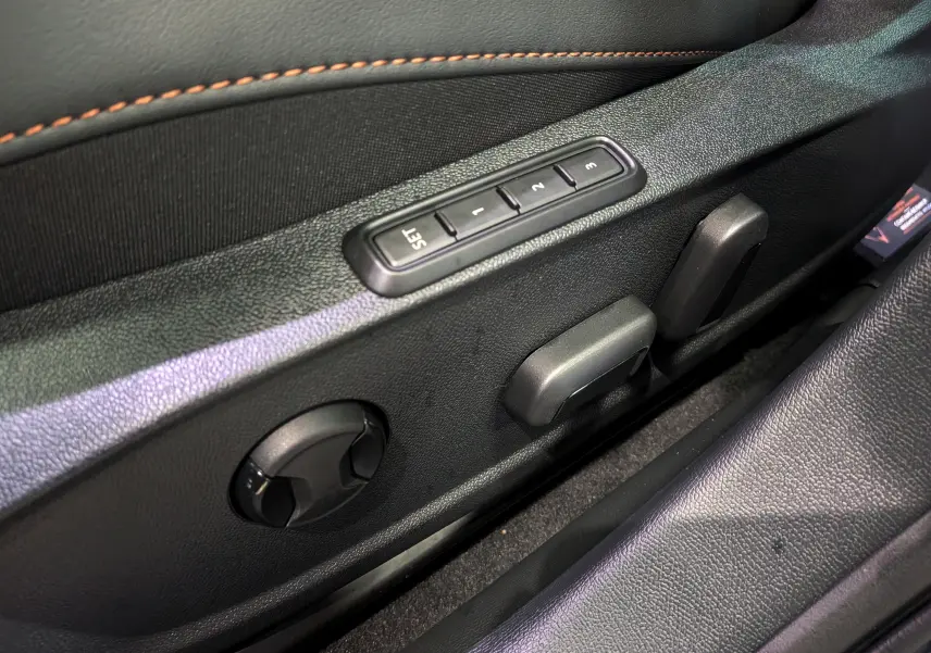 Gros plan sur les commandes de réglage de siège côté gauche en cuir noir avec surpiqûres orange du CUPRA Formentor eHybrid 2025.