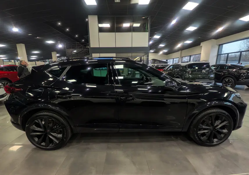 Vue de profil côté gauche d'une CUPRA Formentor eHybrid 2025 en noir minuit avec jantes noires et toit ouvrant en showroom.