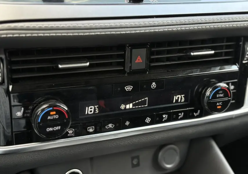 Gros plan sur la console centrale du Nissan Qashqai 2025, affichant la climatisation automatique bi-zone avec commandes digitales.