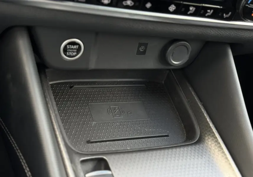 Gros plan sur la console centrale noire du Nissan Qashqai 2025 avec bouton Start/Stop et chargeur sans fil.
