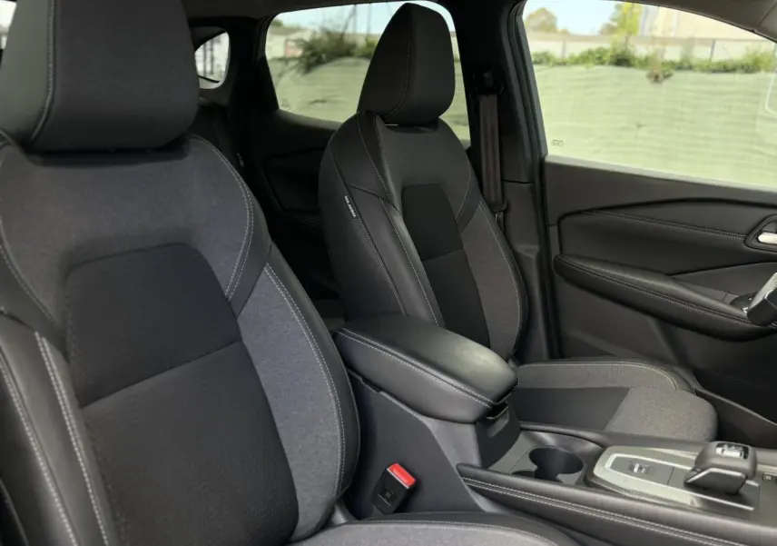 Vue intérieure côté droit des sièges avant gris et noir du Nissan Qashqai 2025 avec accoudoir central et console de boîte automatique.