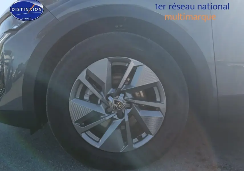 Gros plan sur la roue avant gauche de la Peugeot 408 Hybrid 145 allure e-dcs6 gris sélénite avec jante alu au design moderne.