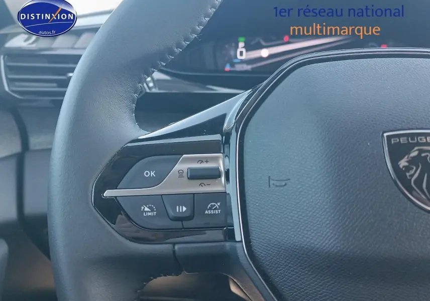 Gros plan sur le volant cuir de la Peugeot 408 Hybrid 145 allure gris sellenium, avec commandes intégrées et tableau de bord numérique.