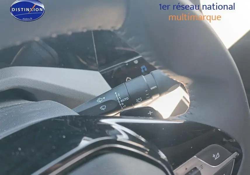 Gros plan sur la manette de commande des essuie-glaces derrière le volant cuir d'une Peugeot 408 gris sélénite.