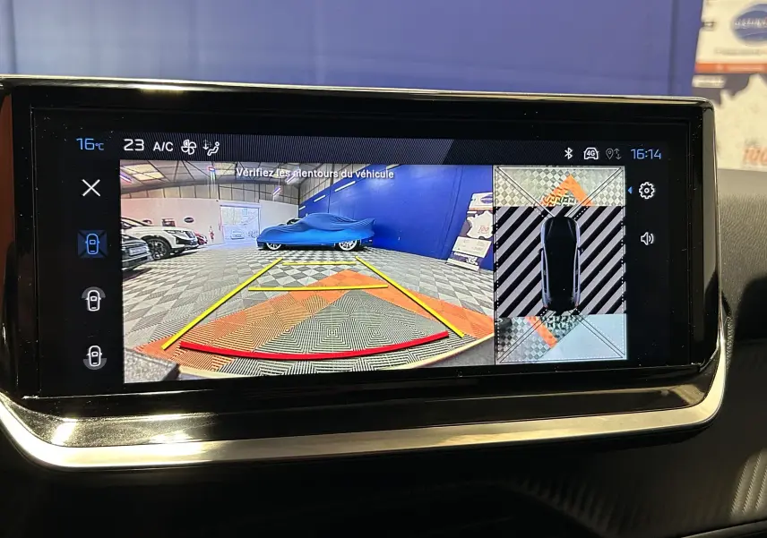 Écran de caméra 360° affichant la vue arrière et la position du Peugeot 208 gris Selenium en stationnement intérieur.