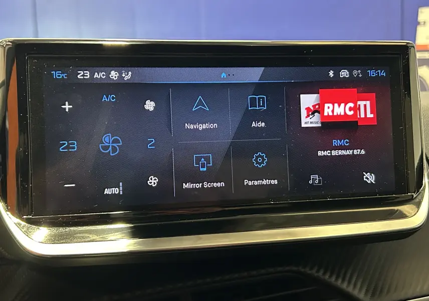 Écran tactile central de la Peugeot 208 2025 affichant la climatisation, navigation et radio RMC à 16h14.