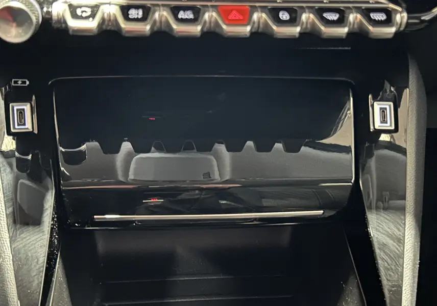 Gros plan sur la console centrale noire brillante de la Peugeot 208 Turbo 100 BVM6 Allure, avec boutons de commande visibles.