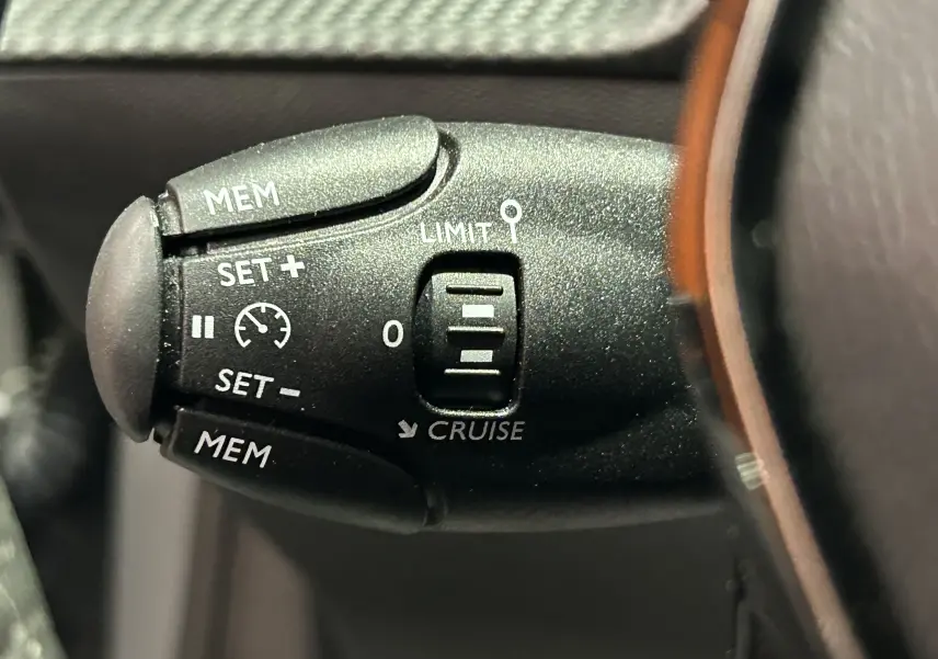 Gros plan sur la commande de régulateur de vitesse noire dans l’habitacle du Peugeot 208 gris Selenium.